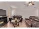 Spacious living room with two brown leather couches, glass table, ceiling fan, and tile floors at 12913 W Columbine Dr, El Mirage, AZ 85335