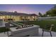 Backyard with a fire pit, outdoor seating, dining area, expansive lawn, and shimmering pool, ideal for gatherings at 13365 N 74Th St, Scottsdale, AZ 85260