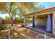 Backyard view of covered patio plus gravel landscaping with privacy wall and shade trees at 14237 W Aster Dr, Surprise, AZ 85379
