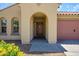 Close-up of home's entrance featuring an arched doorway, wooden door, and well-kept front yard at 14237 W Aster Dr, Surprise, AZ 85379