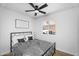 Light-filled bedroom with black metal frame bed and ceiling fan, featuring an exterior view at 14635 N 37Th Pl, Phoenix, AZ 85032
