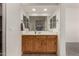 Well-lit bathroom vanity with a large mirror and wood cabinetry offering ample storage at 16222 W Augusta Ave, Litchfield Park, AZ 85340