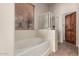 Bathroom featuring a soaking tub, enclosed glass shower, and a window for natural light at 16222 W Augusta Ave, Litchfield Park, AZ 85340