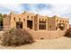 Charming Southwestern-style home featuring distinctive architecture, rock landscaping, and manicured shrubbery at 16222 W Augusta Ave, Litchfield Park, AZ 85340