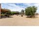 Gravel-covered horse property with shelter and trees under a sunny sky at 16222 W Augusta Ave, Litchfield Park, AZ 85340