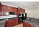 Modern kitchen with dark cabinetry, granite countertops, and black appliances at 16418 W Whitehorn Way, Surprise, AZ 85387