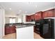 Kitchen featuring granite counters, black appliances, and dark wood cabinets at 16418 W Whitehorn Way, Surprise, AZ 85387