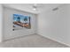 Bright bedroom with neutral carpet, ceiling fan, and large window showcasing palm trees and a neighborhood view at 19920 N 69Th Ave, Glendale, AZ 85308