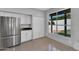 Sunny kitchen with stainless refrigerator, white cabinets, and pool view from the window at 19920 N 69Th Ave, Glendale, AZ 85308