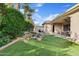 Landscaped backyard with turf lawn, rock garden, and covered patio with table and chairs, perfect for outdoor living at 21912 E Desert Hills Dr, Queen Creek, AZ 85142