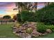 Lush backyard landscape with rock waterfall, bbq, and well-manicured lawn, perfect for outdoor entertaining and relaxation at 21912 E Desert Hills Dr, Queen Creek, AZ 85142
