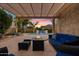 Covered patio featuring comfortable seating and a cozy fire table with backyard pool views at 21912 E Desert Hills Dr, Queen Creek, AZ 85142