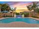 Backyard pool with waterfall feature, lush landscaping, and colorful sunset views at 21912 E Desert Hills Dr, Queen Creek, AZ 85142
