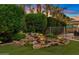 Relaxing water feature with stone accents and vibrant plants, creating a serene backyard retreat with lush foliage at 21912 E Desert Hills Dr, Queen Creek, AZ 85142