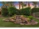 Tranquil water feature with tiered rocks, lush plants, and accent lighting creates a peaceful backyard oasis at 21912 E Desert Hills Dr, Queen Creek, AZ 85142