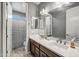 Well-lit bathroom featuring a double sink vanity, large mirror, and tiled shower at 22870 E Sonoqui Blvd, Queen Creek, AZ 85142