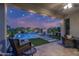 Inviting covered patio with outdoor seating overlooking a beautiful pool with waterfall feature and manicured landscaping at 2339 E Questa Dr, Phoenix, AZ 85024