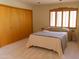 Bright bedroom featuring a light pink bedspread, wood shuttered windows, and a closet with louvered doors at 2430 N 56Th St, Phoenix, AZ 85008