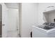 Bright laundry room with modern, front-loading washer and tile floors at 24559 W Flores Dr, Buckeye, AZ 85326