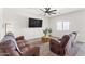 Bright living room featuring neutral carpet, ceiling fan, TV, and comfortable seating at 24559 W Flores Dr, Buckeye, AZ 85326