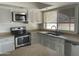 Well-lit kitchen featuring stainless steel appliances, window with blinds, and neutral countertops at 3738 W Danbury Dr, Glendale, AZ 85308