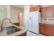 Functional kitchen featuring wooden cabinetry, a stainless steel sink, and a view to the laundry room at 440 S Val Vista Dr # 11, Mesa, AZ 85204