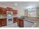 Bright kitchen featuring wooden cabinetry, white appliances, granite countertops and a stylish tile backsplash at 440 S Val Vista Dr # 11, Mesa, AZ 85204