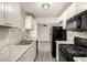 Well lit kitchen with white cabinets and black appliances, granite countertops, and gray wood flooring at 6139 N 31St Dr, Phoenix, AZ 85017