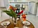 Close up of dining table with vase of flowers, settings, and a view into the kitchen at 6626 W Monona Dr, Glendale, AZ 85308