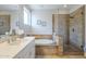 Bright bathroom with double vanity, travertine tiled accent wall, walk-in shower, and jacuzzi tub at 6847 S 27Th Pl, Phoenix, AZ 85042
