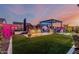 Backyard at dusk featuring artificial grass, pergola, outdoor kitchen, and lighted plants and fencing at 8127 E June St, Mesa, AZ 85207