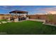 Spacious backyard with lush green turf, outdoor kitchen, fireplace, and comfortable seating under a wooden pergola at 8127 E June St, Mesa, AZ 85207