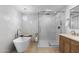 Bright bathroom with modern shower, soaker tub, and vanity with stone counters, all illuminated by a decorative chandelier at 8430 E Fairmount Ave, Scottsdale, AZ 85251