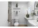 Well-lit bathroom with decorative vases on floating shelves, a tile shower, and a traditional toilet and sink at 8430 E Fairmount Ave, Scottsdale, AZ 85251