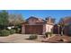 Charming single-Gathering home featuring a tile roof, brown garage door, desert landscaping, and a private, gated side entrance at 9967 W Devonshire Ave, Phoenix, AZ 85037
