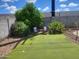 Picturesque backyard with artificial turf, mature greenery, two chairs and a small palm tree at 10201 S 49Th St, Phoenix, AZ 85044