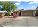Traditional tan stucco home with tile roof, desert landscaping, large driveway, and attached two-car garage at 10239 E Salt Bush Dr, Scottsdale, AZ 85255