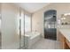 Bright bathroom showcasing a glass-enclosed shower, a soaking tub, and access to the main bedroom at 1028 W Chilton Ave, Gilbert, AZ 85233