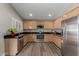 Bright kitchen with wood cabinets, stainless steel appliances, dark countertops and wood-look flooring at 1028 W Chilton Ave, Gilbert, AZ 85233