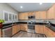 Modern kitchen featuring stainless steel appliances, wood cabinets, and black countertops at 1028 W Chilton Ave, Gilbert, AZ 85233