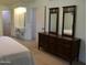 Bedroom with dark wood dresser and vanity area leading to the bathroom at 10428 W Camelot Cir, Sun City, AZ 85351