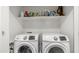 Bright laundry room featuring white front-load washer and dryer with storage shelf, perfect for efficient chores at 1250 N Abbey Ln # 275, Chandler, AZ 85226