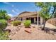 Lush backyard featuring desert landscaping, a rock drainage feature, and a large covered patio at 17429 W Red Bird Rd, Surprise, AZ 85387