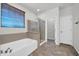 Bathroom featuring a soaking tub, glass-enclosed shower, and neutral color palette offers spa-like serenity at 17429 W Red Bird Rd, Surprise, AZ 85387