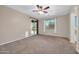 Neutral bedroom offers a ceiling fan, carpet, with views of the backyard through the window and slider at 17429 W Red Bird Rd, Surprise, AZ 85387