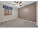 Bedroom with neutral carpet, ceiling fan, and window with patterned valence at 17429 W Red Bird Rd, Surprise, AZ 85387