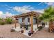 Outdoor dining area under a wooden pergola, surrounded by desert landscaping and blue skies at 18415 W Surprise Farms N Loop, Surprise, AZ 85388