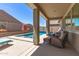 Relaxing covered patio space with wicker furniture overlooks a sparkling pool and landscaped backyard at 22495 E Silver Creek Ln, Queen Creek, AZ 85142