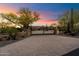 Entrance to desert estate featuring a circular driveway, iron gates, mature trees and desert landscaping at twilight at 22610 N 80Th Pl, Scottsdale, AZ 85255