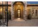 Inviting home entrance featuring a stone archway, elegant lighting, and wrought iron gate and door at 22610 N 80Th Pl, Scottsdale, AZ 85255